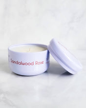 Load image into Gallery viewer, A compact white travel tin candle from Infusion Candle Co., labeled 'Sandalwood Rose' featuring a blend of rose and woody sandalwood scents. The candle is displayed with its lid partially open, showcasing the smooth soy wax. This portable candle, handmade in Illinois, provides a calming floral and earthy aroma, perfect for taking a serene and relaxing atmosphere wherever you go. Sandalwood Rose travel tin candle by Infusion Candle Co.