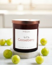 Load image into Gallery viewer, A beautifully crafted amber jar candle from Infusion Candle Co., labeled 'Gooseberry' with notes of red currant, lemon peel, and geranium. The candle is surrounded by fresh, green gooseberries, highlighting its natural and refreshing scent. This soy wax candle, handmade in Illinois, exudes a vibrant and zesty aroma perfect for brightening any space. Gooseberry candle by Infusion Candle Co.