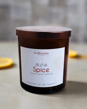 Load image into Gallery viewer, A rich amber jar candle from Infusion Candle Co., labeled 'Spice' with aromatic notes of lemon, ginger, and saffron. The candle is elegantly placed with slices of fresh lemon nearby, emphasizing its spicy and citrusy fragrance. This soy wax candle, handmade in Illinois, is perfect for creating a warm and inviting atmosphere with its unique blend of spice and zest. Spice candle by Infusion Candle Co.